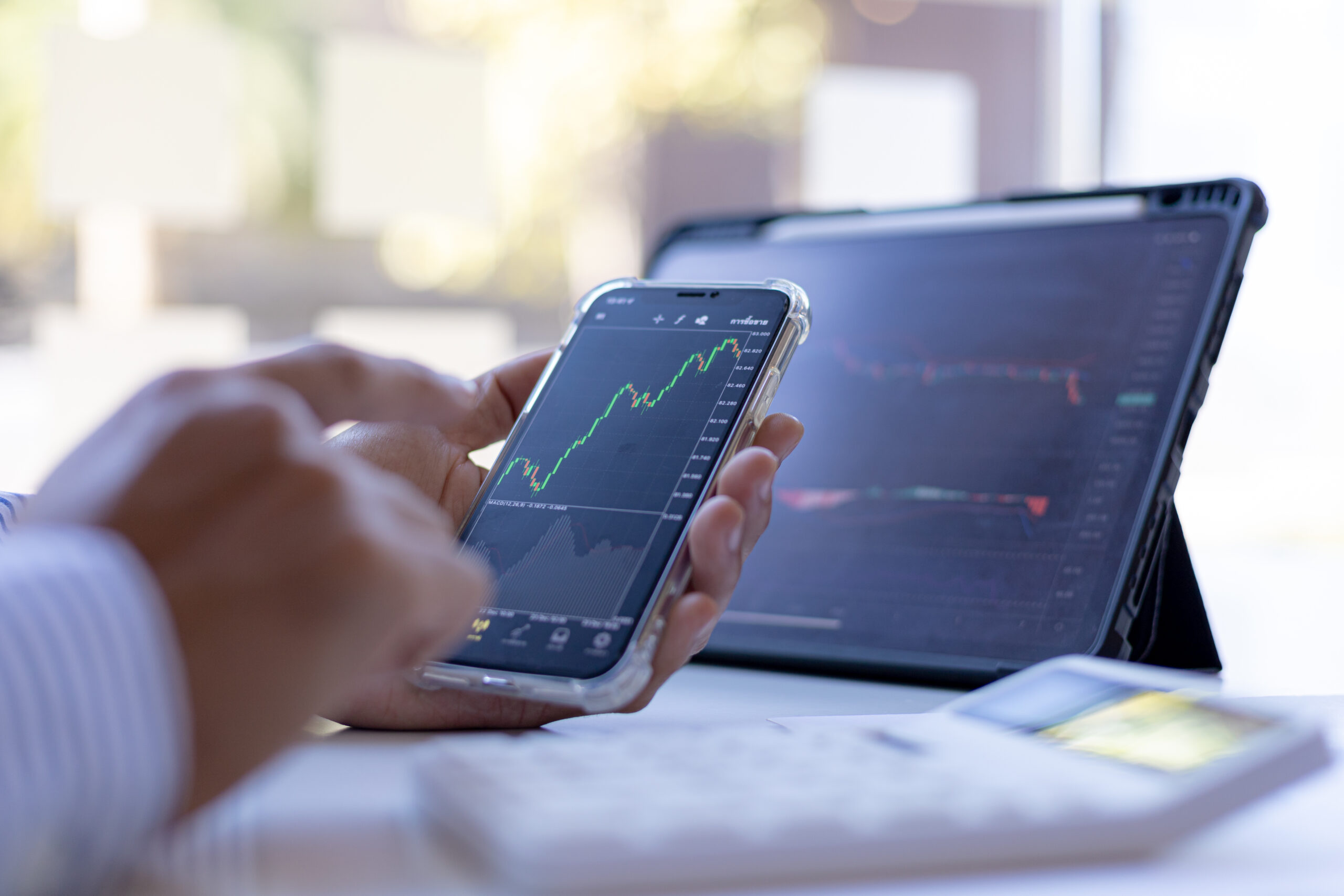 An investor is looking at stock charts on mobile phones and tablets, he is a stock investor, he trades stocks by analyzing the charts and using indicators to enter trades. Stock investment idea.